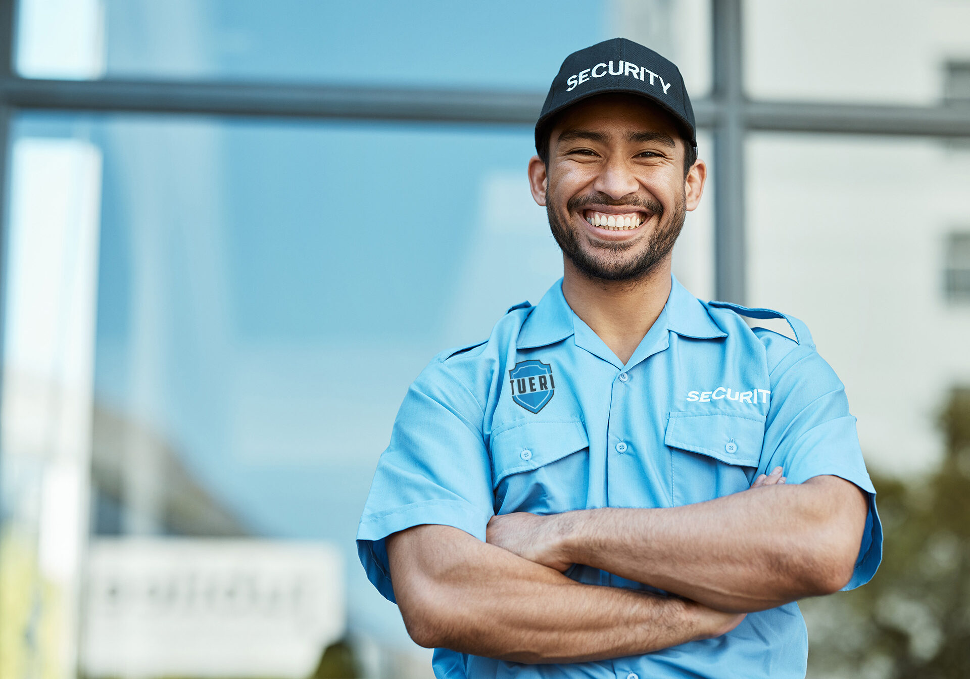 Happy man, portrait and security guard with arms crossed in city for career safety or outdoor protection. Male person, police or officer smile in confidence, law enforcement or patrol in urban town.